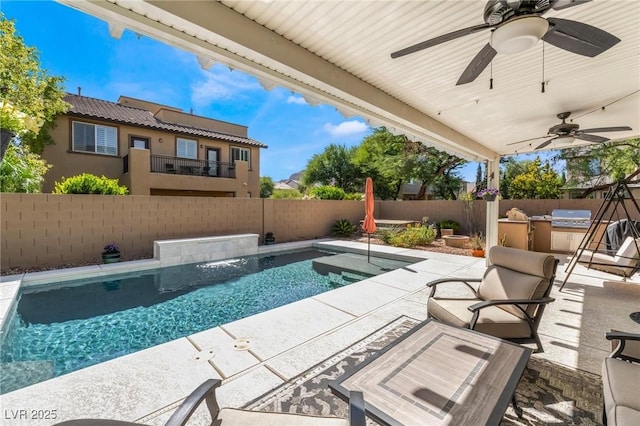 view of swimming pool featuring pool water feature, an outdoor kitchen, a grill, and a patio area