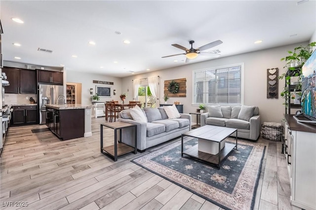 living room with ceiling fan and light hardwood / wood-style flooring