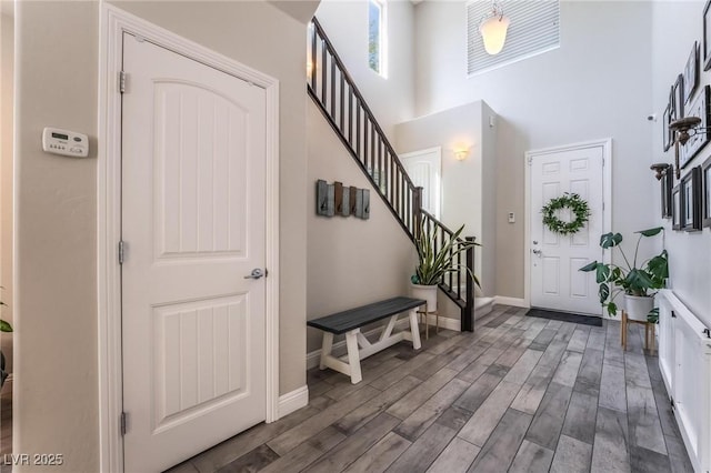 foyer entrance featuring a towering ceiling and dark wood-type flooring