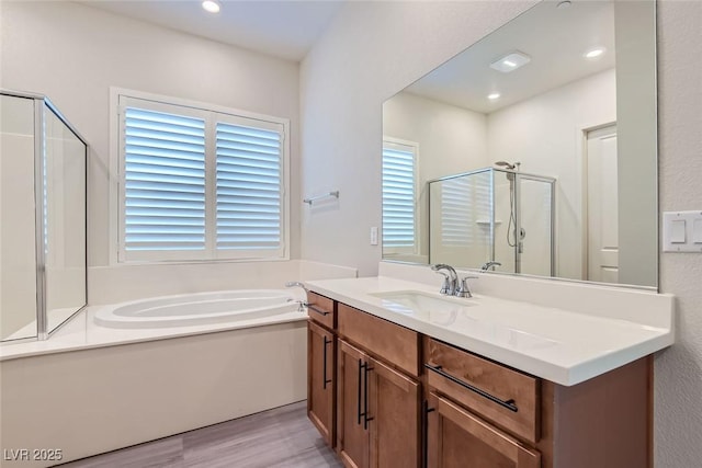 bathroom with hardwood / wood-style floors, vanity, and independent shower and bath