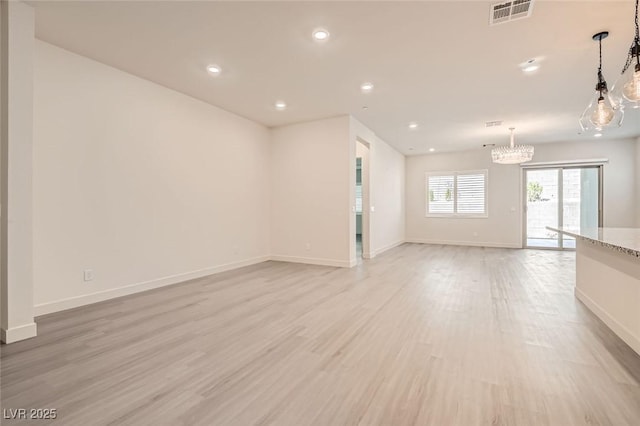 unfurnished living room with a notable chandelier and light wood-type flooring