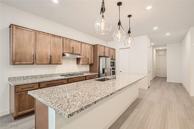 kitchen featuring pendant lighting, light stone countertops, sink, and appliances with stainless steel finishes