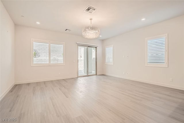 empty room featuring light wood-type flooring and a chandelier