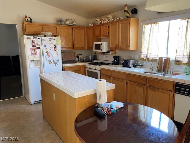 kitchen with tile counters, sink, vaulted ceiling, white appliances, and a kitchen island