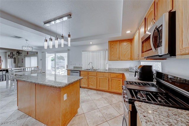 kitchen featuring light stone counters, a textured ceiling, stainless steel appliances, a raised ceiling, and hanging light fixtures