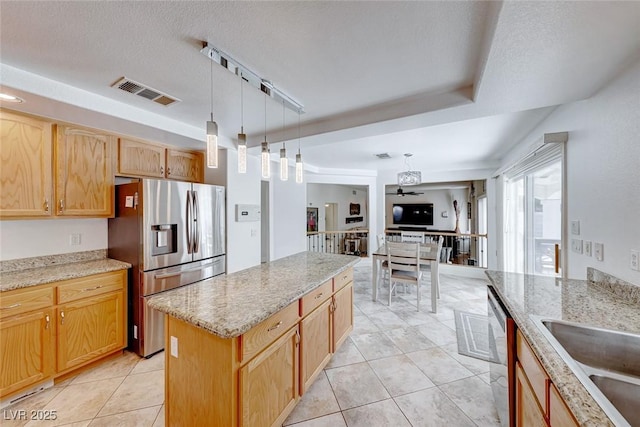 kitchen with pendant lighting, a center island, rail lighting, light stone countertops, and stainless steel appliances