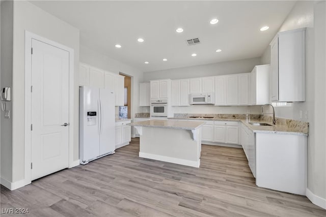 kitchen featuring a center island, white cabinets, white appliances, and sink