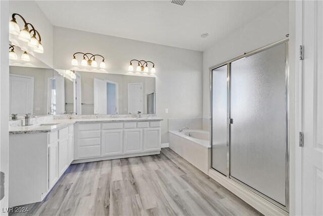 bathroom with hardwood / wood-style flooring, vanity, and plus walk in shower