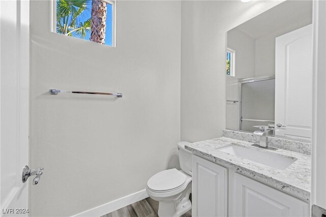 bathroom with vanity, hardwood / wood-style flooring, toilet, and an enclosed shower