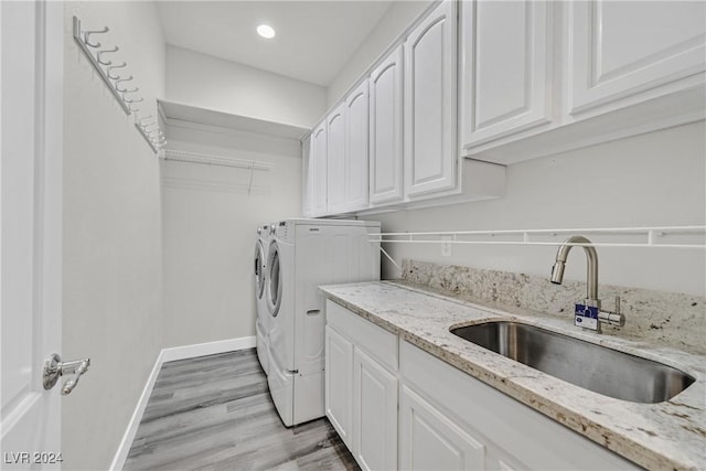 laundry area with separate washer and dryer, sink, cabinets, and light hardwood / wood-style floors