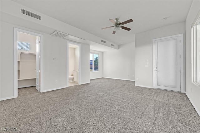 interior space featuring a walk in closet, ceiling fan, connected bathroom, carpet floors, and a closet