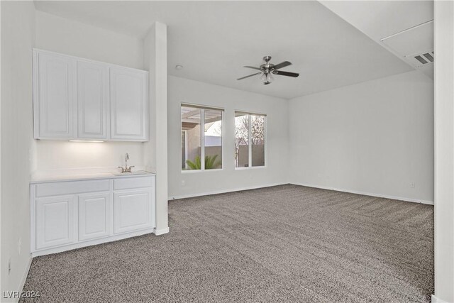 unfurnished living room with carpet, ceiling fan, and sink