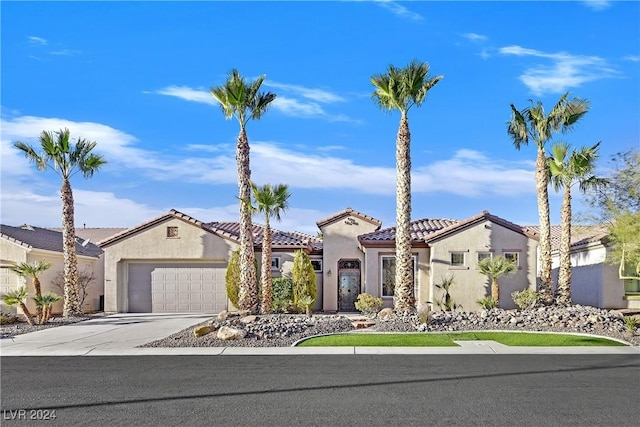 mediterranean / spanish-style home featuring a tile roof, driveway, an attached garage, and stucco siding