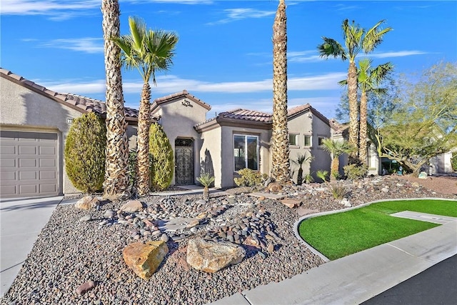 mediterranean / spanish house with a garage, a tile roof, and stucco siding