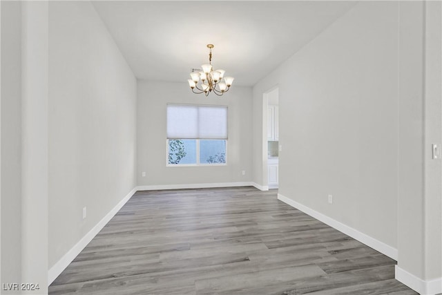 empty room featuring a chandelier and hardwood / wood-style flooring