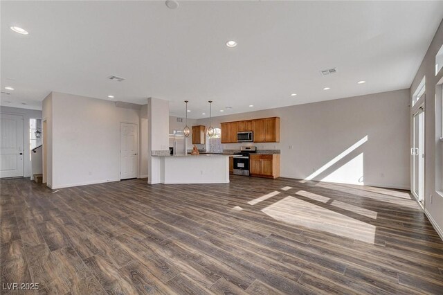 unfurnished living room featuring plenty of natural light and dark wood-type flooring