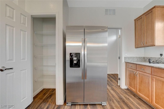 kitchen with light stone countertops, stainless steel fridge, and dark hardwood / wood-style flooring