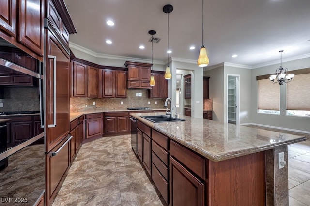 kitchen featuring sink, a chandelier, pendant lighting, a kitchen island with sink, and ornamental molding