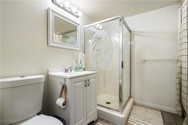 bathroom featuring vanity, toilet, and a shower with shower door