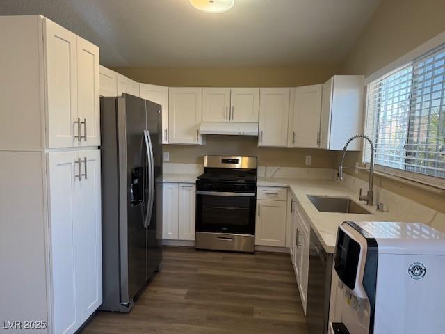 kitchen with sink, stainless steel appliances, dark hardwood / wood-style flooring, vaulted ceiling, and white cabinets