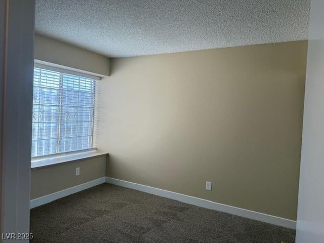 empty room featuring dark colored carpet and a textured ceiling