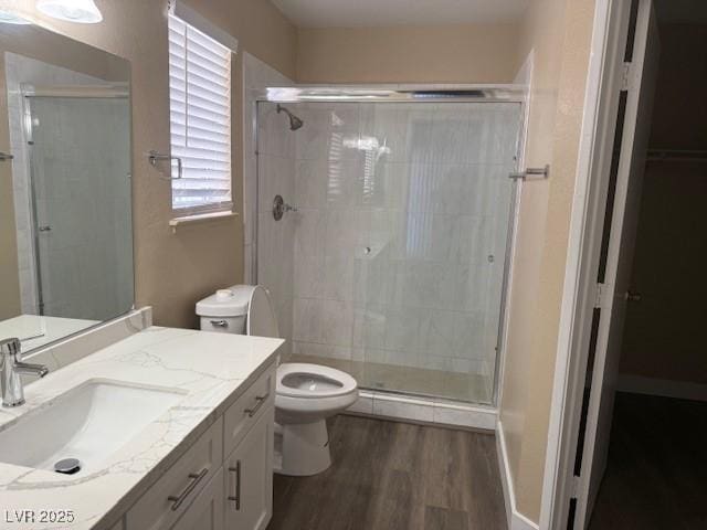 bathroom featuring hardwood / wood-style floors, vanity, a shower with door, and toilet