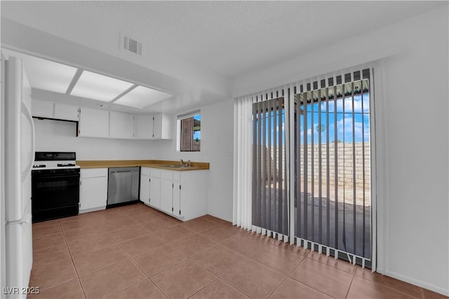 kitchen with black gas range oven, dishwasher, white fridge, white cabinetry, and light tile patterned flooring