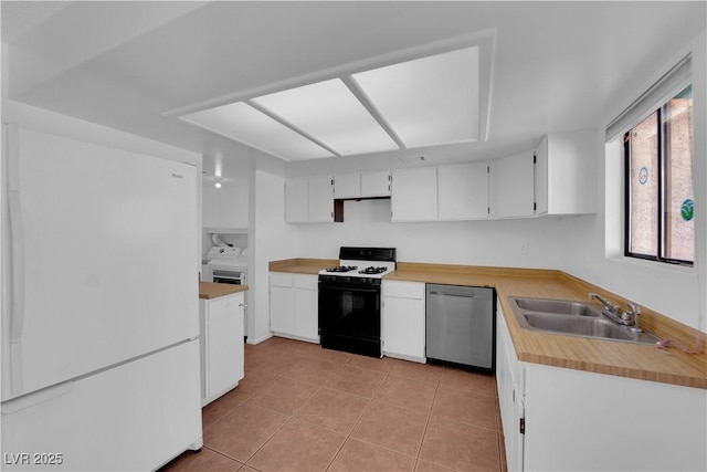 kitchen featuring white appliances, sink, washer and dryer, light tile patterned floors, and white cabinetry