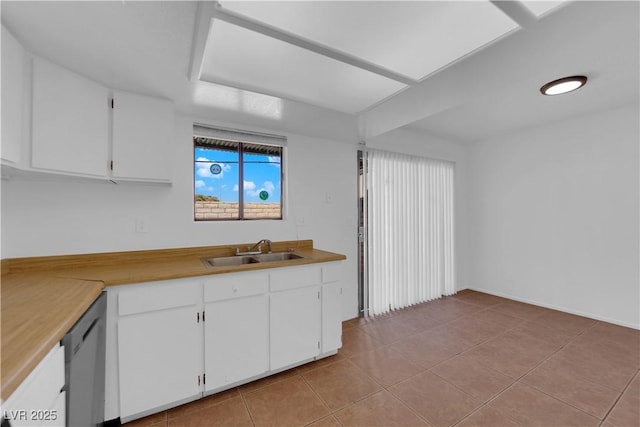 kitchen with dishwasher, white cabinetry, sink, and light tile patterned floors