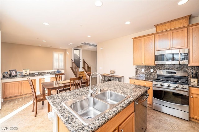 kitchen featuring tasteful backsplash, appliances with stainless steel finishes, sink, and a kitchen island with sink