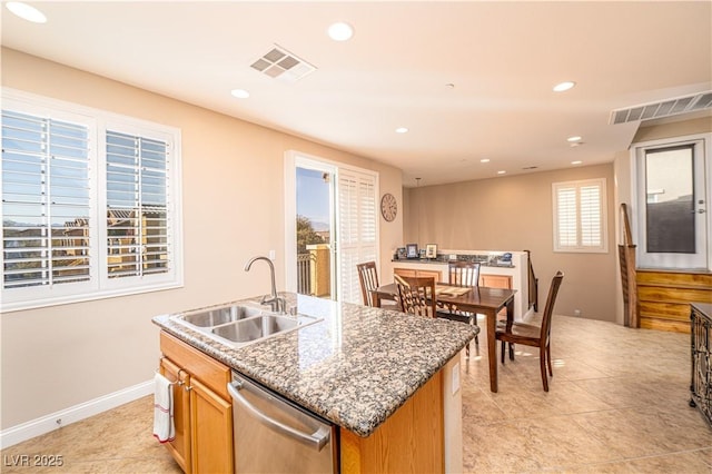 kitchen featuring stone counters, light tile patterned flooring, dishwasher, sink, and a kitchen island with sink