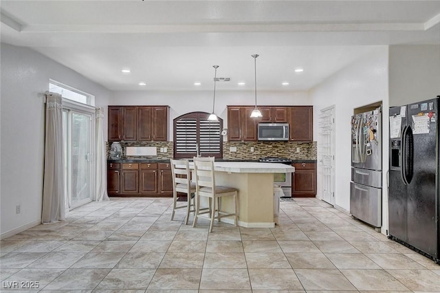 kitchen with tasteful backsplash, a center island, stainless steel appliances, and decorative light fixtures