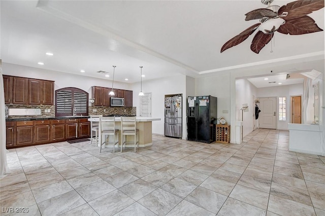 kitchen with hanging light fixtures, a kitchen bar, decorative backsplash, a kitchen island, and appliances with stainless steel finishes