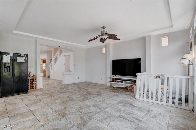 living room featuring a raised ceiling and ceiling fan