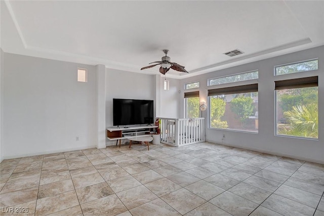 unfurnished living room featuring ceiling fan, light tile patterned flooring, and a tray ceiling