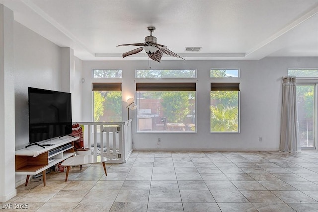 living room with light tile patterned floors, a tray ceiling, ceiling fan, and a healthy amount of sunlight