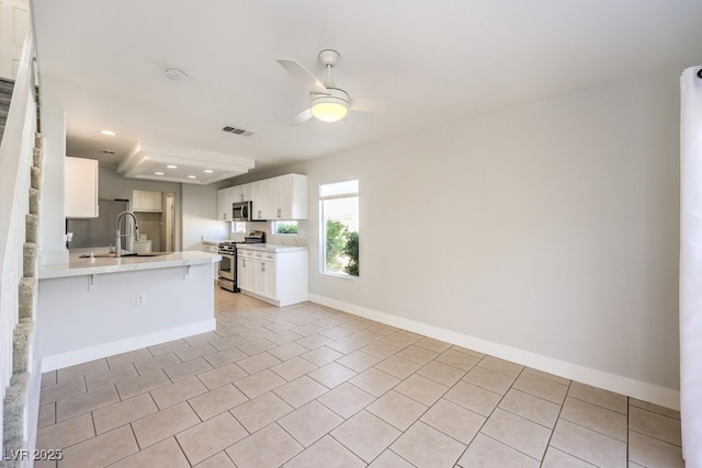 kitchen featuring kitchen peninsula, appliances with stainless steel finishes, a kitchen breakfast bar, sink, and white cabinetry