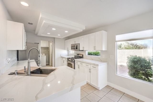 kitchen with white cabinetry, sink, stainless steel appliances, and light stone counters