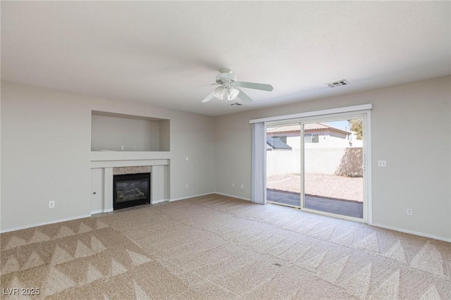 unfurnished living room with a fireplace, light colored carpet, and ceiling fan