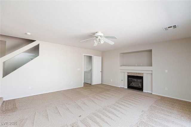 unfurnished living room with carpet flooring, ceiling fan, washer / clothes dryer, and a tile fireplace