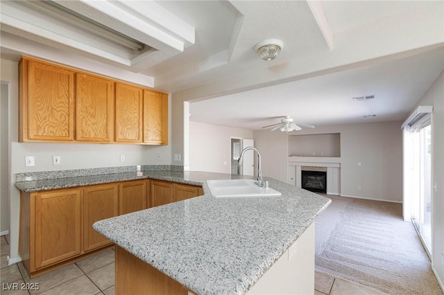 kitchen with sink, ceiling fan, light stone countertops, light tile patterned flooring, and kitchen peninsula