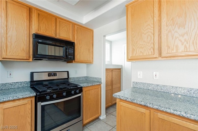 kitchen featuring light tile patterned flooring, light stone counters, light brown cabinets, and stainless steel range with gas stovetop