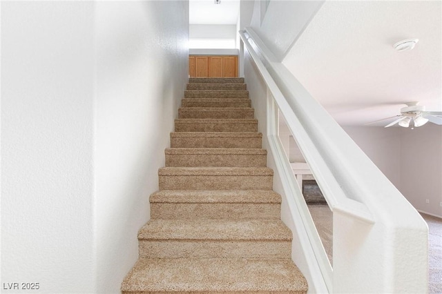 stairs featuring ceiling fan