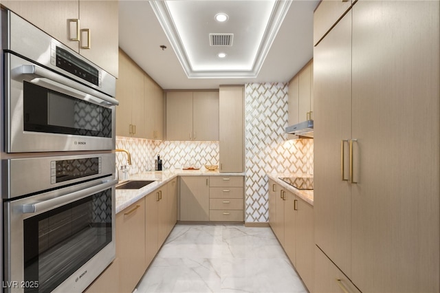 kitchen with sink, a raised ceiling, double oven, cream cabinets, and black electric stovetop