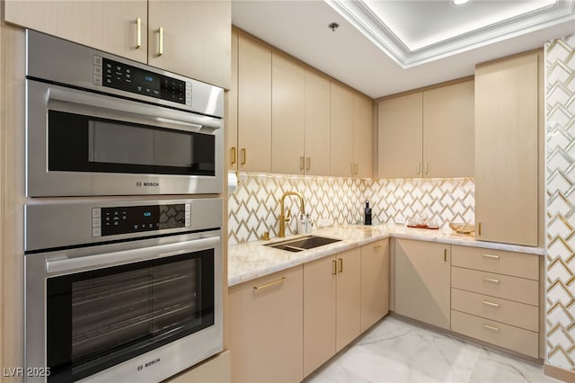 kitchen with tasteful backsplash, light stone countertops, cream cabinets, and sink