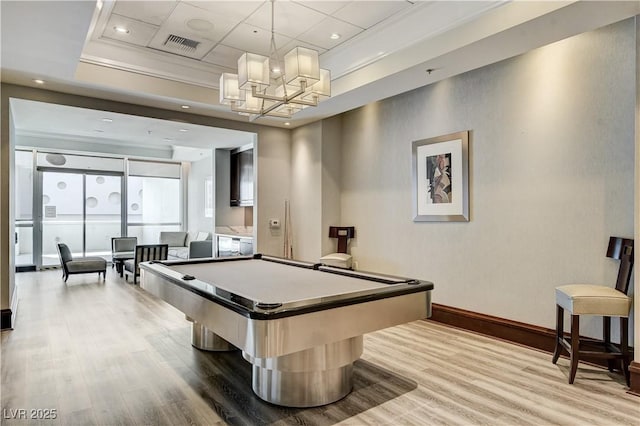 playroom with a raised ceiling, wood-type flooring, a notable chandelier, and pool table