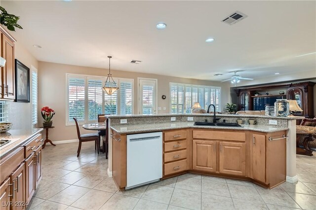 kitchen with light stone counters, dishwasher, pendant lighting, ceiling fan, and sink