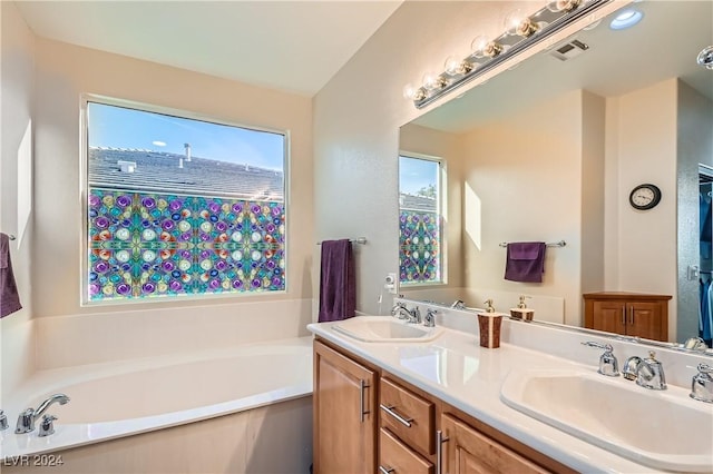 bathroom with a tub to relax in, a wealth of natural light, and vanity