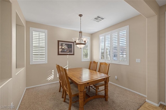 carpeted dining space with an inviting chandelier