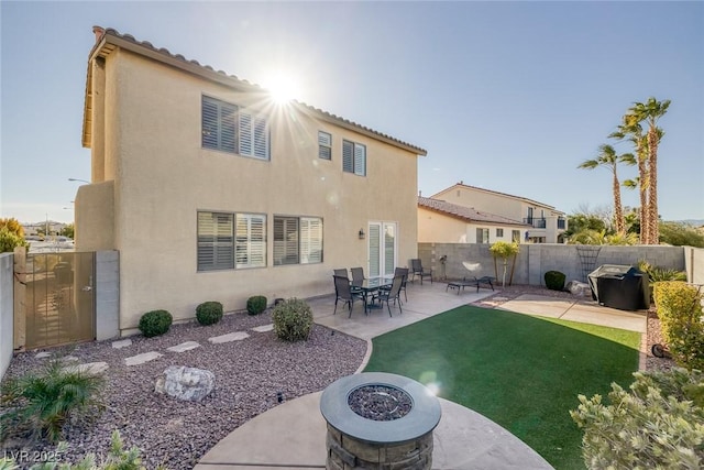 back of property with a patio area, a yard, and an outdoor fire pit